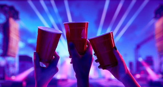 Fondo de una fiesta nocturna, tres vasos plásticos rojos, en el aire, en señal de brindis.