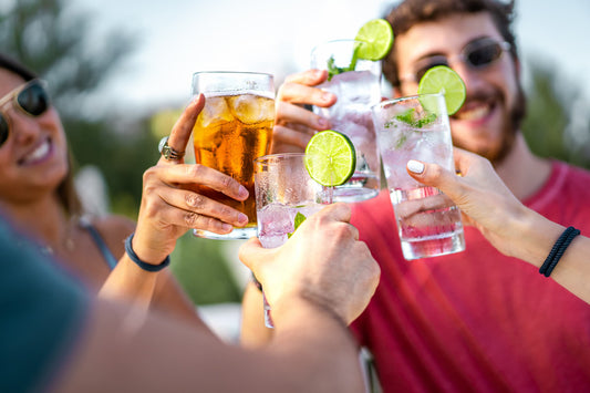 grupo de cuatro amigos, brindad con los vasos en alto. Usan lentes, verano.