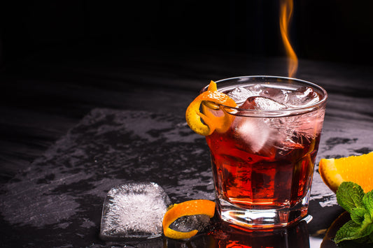Negroni con hielo grande y twist de naranja servido en vaso old fashioned, cóctel clásico con gin chileno artesanal.